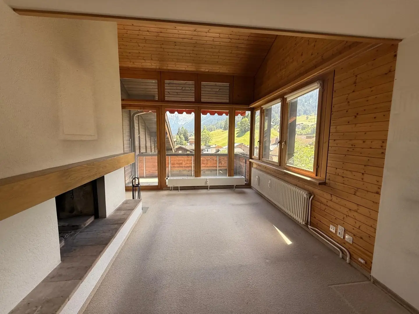 Geräumtes Wohnzimmer mit Kamin und grossen Fenstern